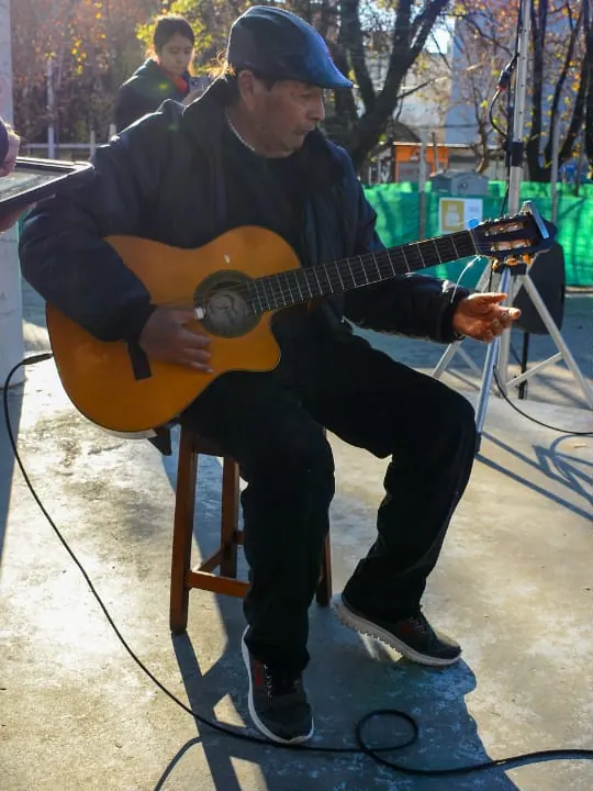Guitarrista criollo sentado tocando durante un show de folklore al aire libre