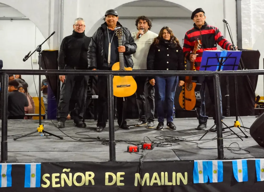 Grupo de músicos folklóricos en el escenario del Señor de Mailín con la bandera argentina